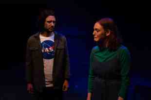 two actors on stage, one male and one female, looking concerned and upset