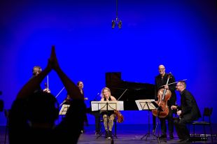 a group of classical musicans on stage and an audio engineer recording their concert