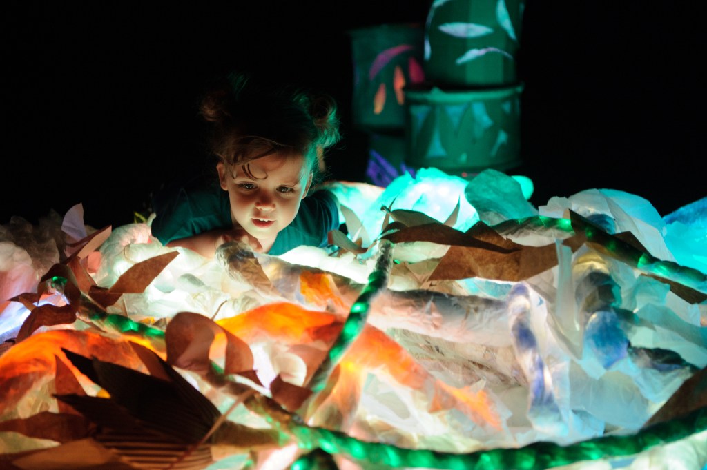 a child playing with coloured paper in the dark