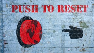 Text reading 'Push to reset' with a large red button written ona white crick wall