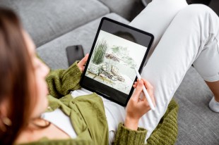 Person on a couch illustrating on a tablet