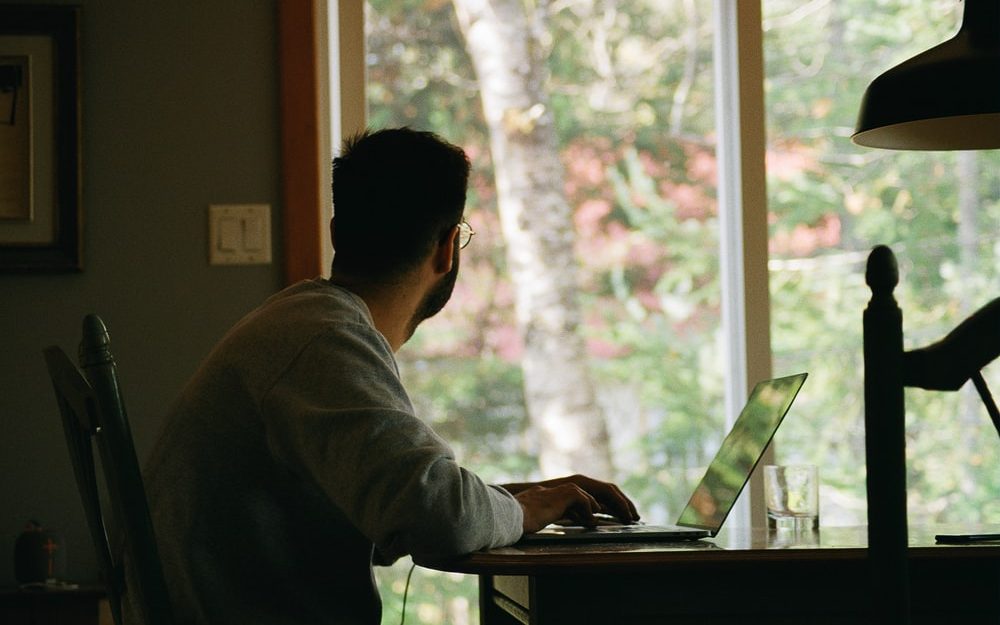 Man looks out window from his computer screen