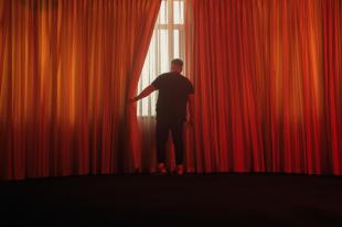 a man pulling back a big red curtain