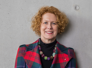 Woman in tartan jacket on a plain background