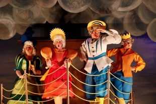 Four figures on a stage wear bright colours