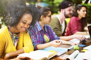 a group of young students sitting at an outdoor table studying