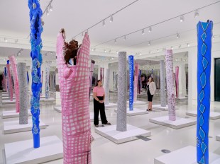 Two women stand in installation of bark painting at NGV Interntional, Melbourne