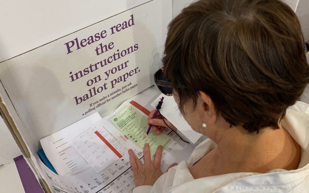 A woman fills out a ballot paper