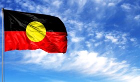 Aboriginal flag against blue sky.