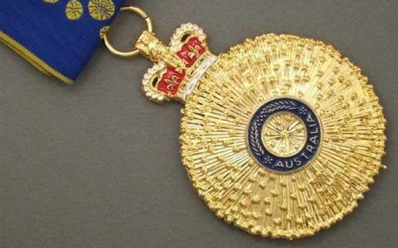 A photo of a gold medal suspended from a blue pin. Australia Day Honours