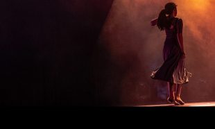 A female dancer on stage under smoky spotlight