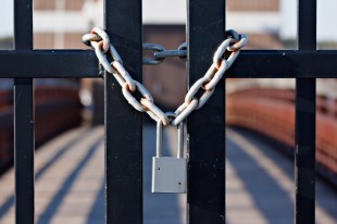 An oron gate locked by a padlock and chain.