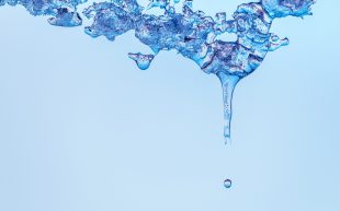 A droplet of water falls from melting ice.