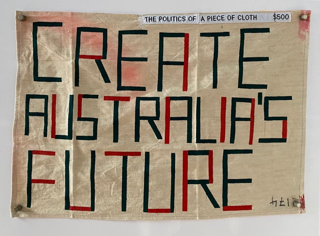 A fabrix sign that reads Create Australia's Future with smaller test reading The Politics of a piece of cloth.