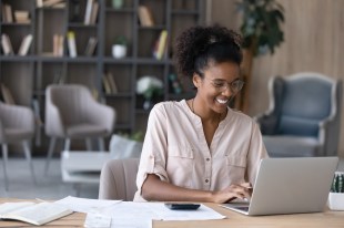 A smiling woman working on a laptop