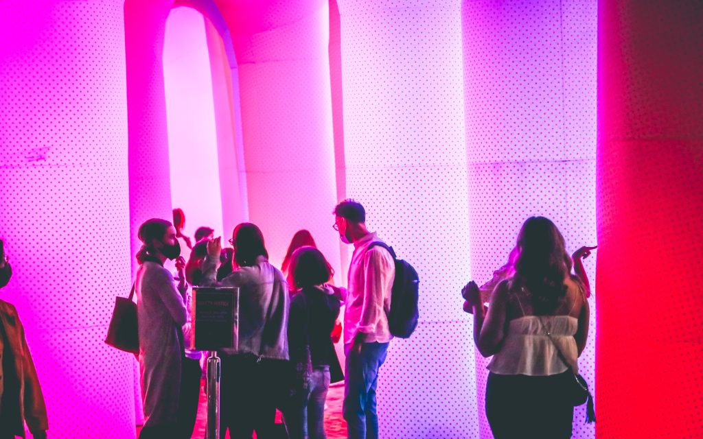 a group of people standing beside a bright art installation