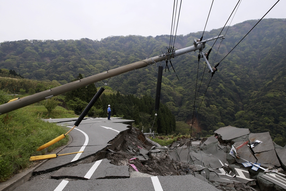 Flooding has collapsed a road, which has also brought down powerlines as the asphalt crumbles away.