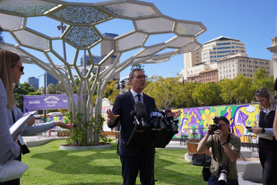 A suited man (SA Premier Steven Marshall) speaks a t microphone in front of a sculpture