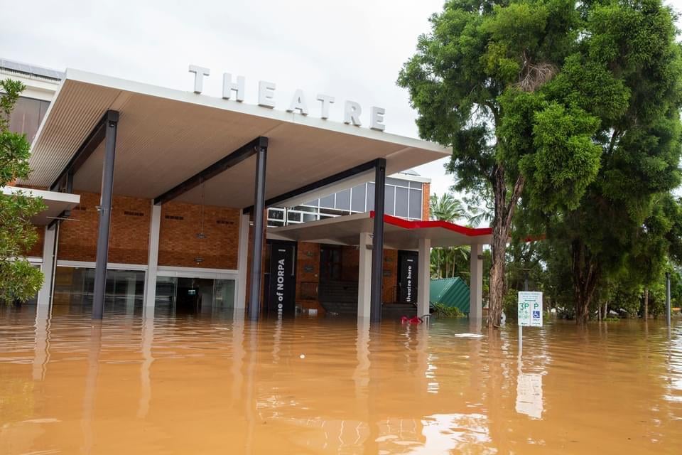 Muddy brown water dominiates the phot, which shows a theatre half-sumerged by floods.