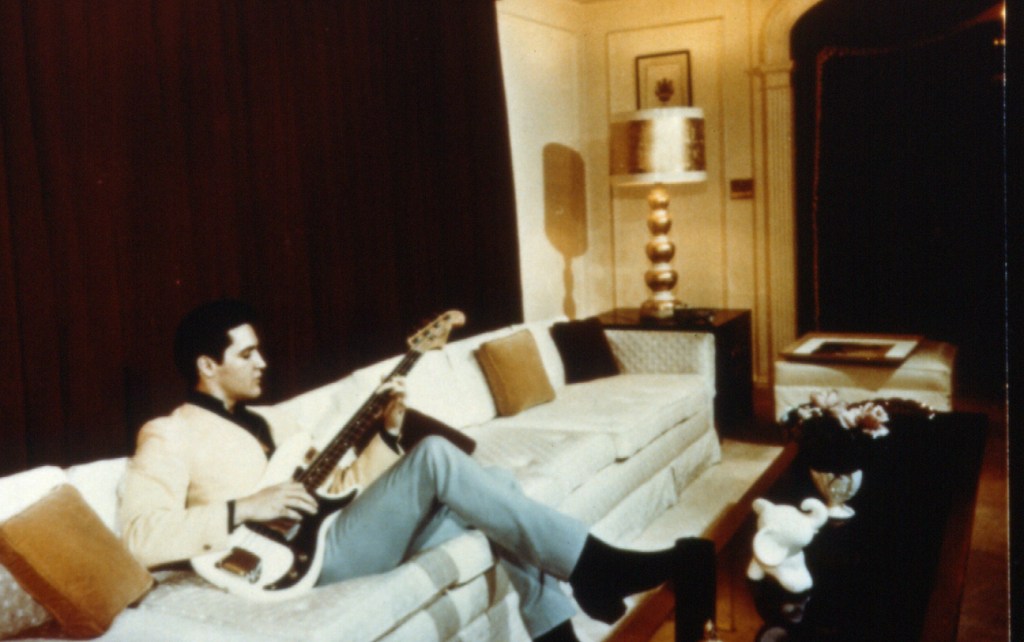 Elvis playing his guitar at home.
