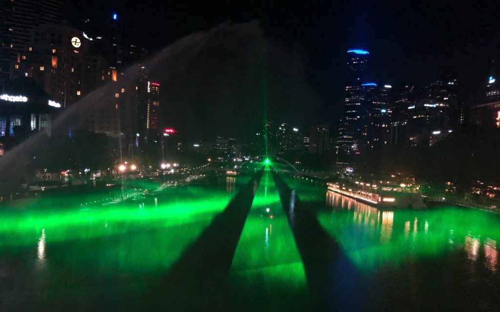 A vivid green laser beam almost a kilometre long shines above the Yarra River at night.