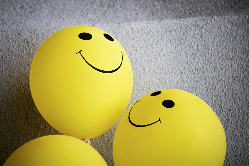 Three yellow balloons, with two having smiley faces