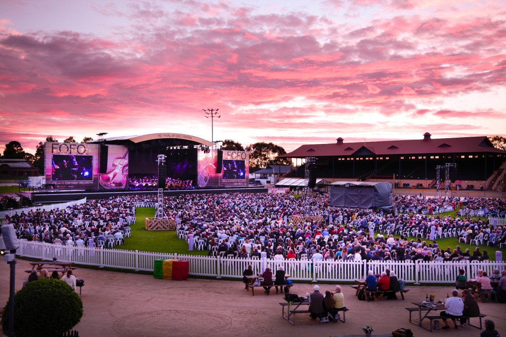 An audience that's part music festival, part concert gathers under sunset-dappled clouds at the Adelaide Showgrounds.