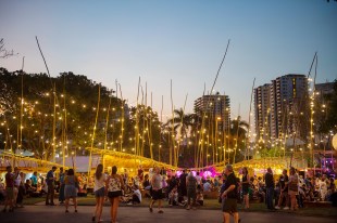 Crowds gather beneath glittering lights hanging beneath the soft evening sky.