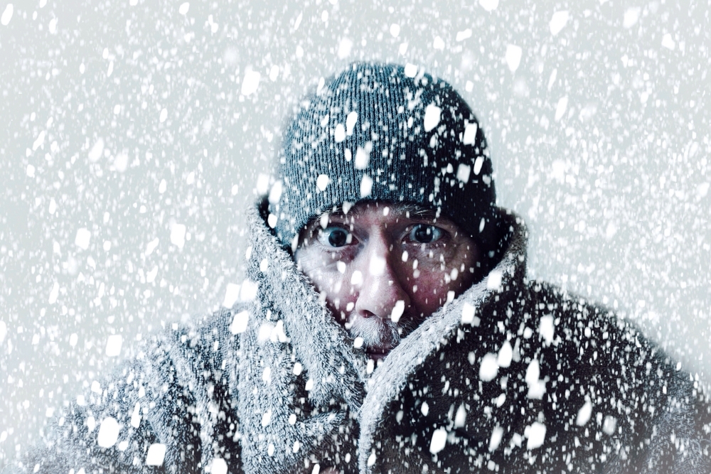 Wintery scene of shivering man in snowstorm