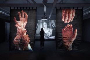 Person watching video with tapestry banners displaying hands