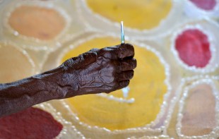 A close up of an Aboriginal artist's hand creating a new painting.