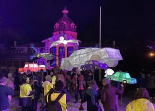 Colourful lanterns in the sahpes of cars and birds are carried through Bathurst's streets at night.