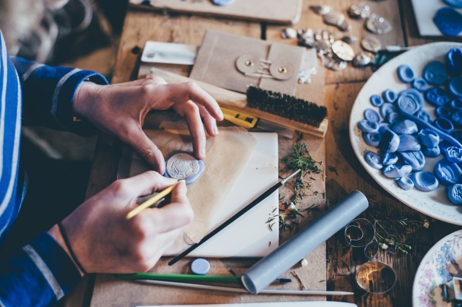 An artist's hands as they work on small ceramic art pieces