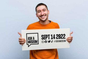 Man holding placard saying 'Ask a Museum'