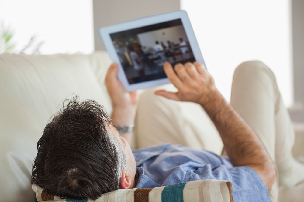 man laying on couch looking on tablet