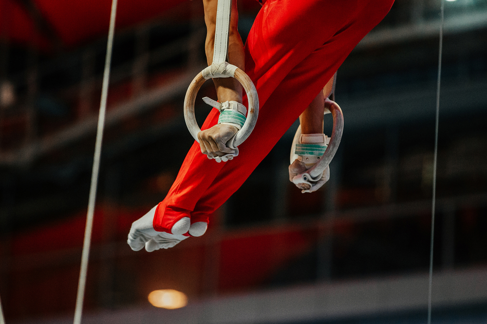 A close-up photo of an athlete tightly gripping gymnastic rings.