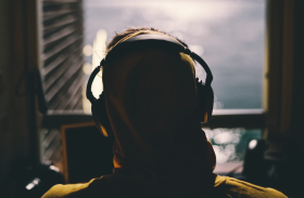 Podcast. Image is the back of someone's head wearing headphones.