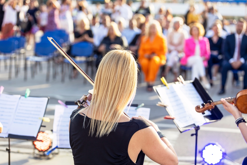 violinist playing to crowd in outdoor space