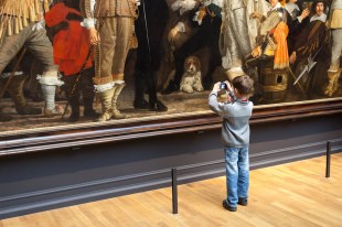 young boy taking photograph of painting
