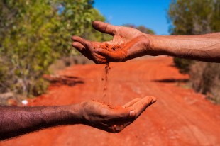 hands with red soil in Australia's desert country