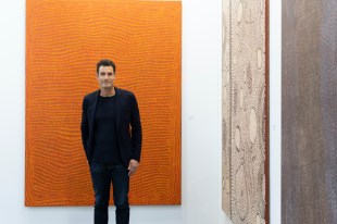 Art entrepreneur Paul Becker starting in front of Aboriginal paintings