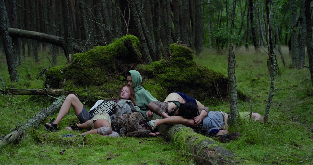 Film still of bodies laying in natural environment