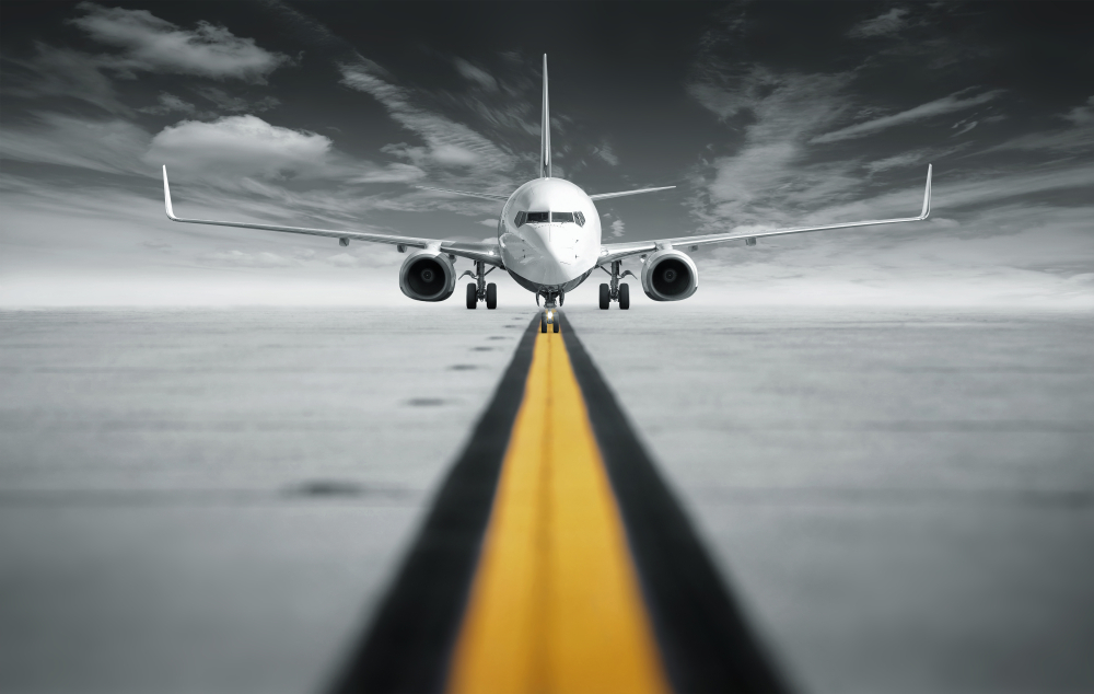 A dynamic image taken from a low angle of a plane on a runway, about to take off.