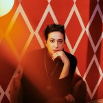 Le designer indien Mahdavi photographié sur du papier peint rouge à motifs