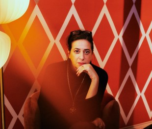 Designer India Mahdavi photographed against patterned red wallpaper
