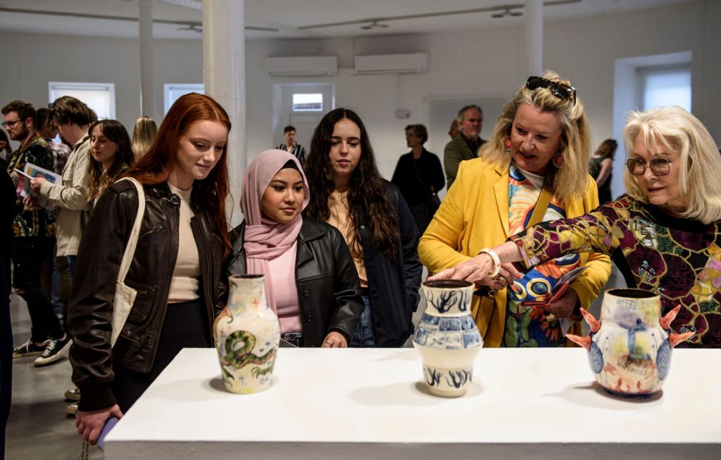 National Art School. Image is a group of women behind a table and looking at the ceramics displayed on it.