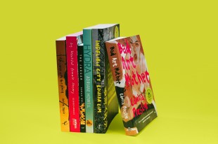 The spines of six books are shown lined up against a greenish-yellow background.