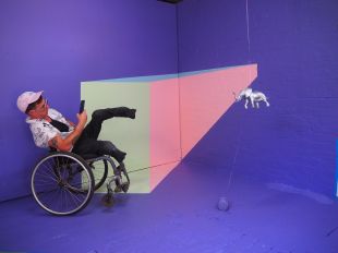 artist Bruno Booth in a wheelchair, in a painted purple room