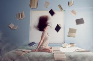 blurred picture of woman on bed with books 'raining' around her