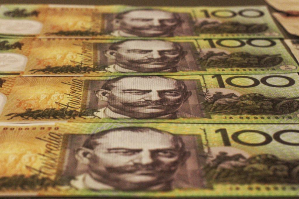 Australian $100 notes laid out in a visually pleasing pattern.